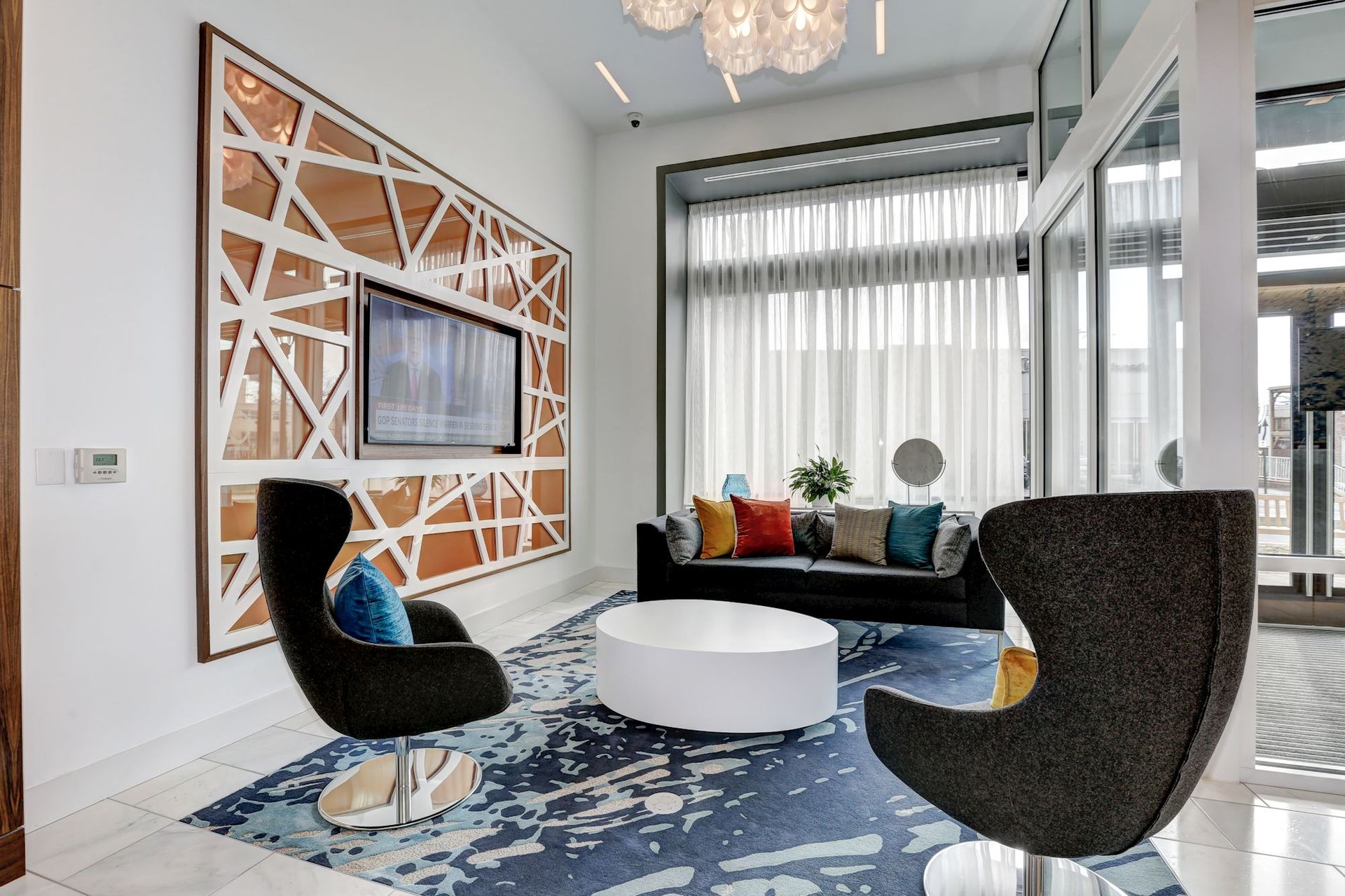 A community room with a couch, chairs, table and television at Solaire 7077 Woodmont in Bethesda, MD.