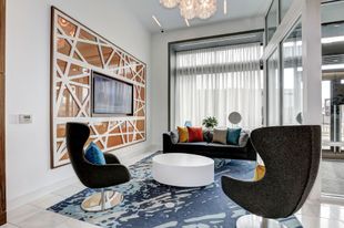 A community room with a couch, chairs, table and television at Solaire 7077 Woodmont in Bethesda, MD.