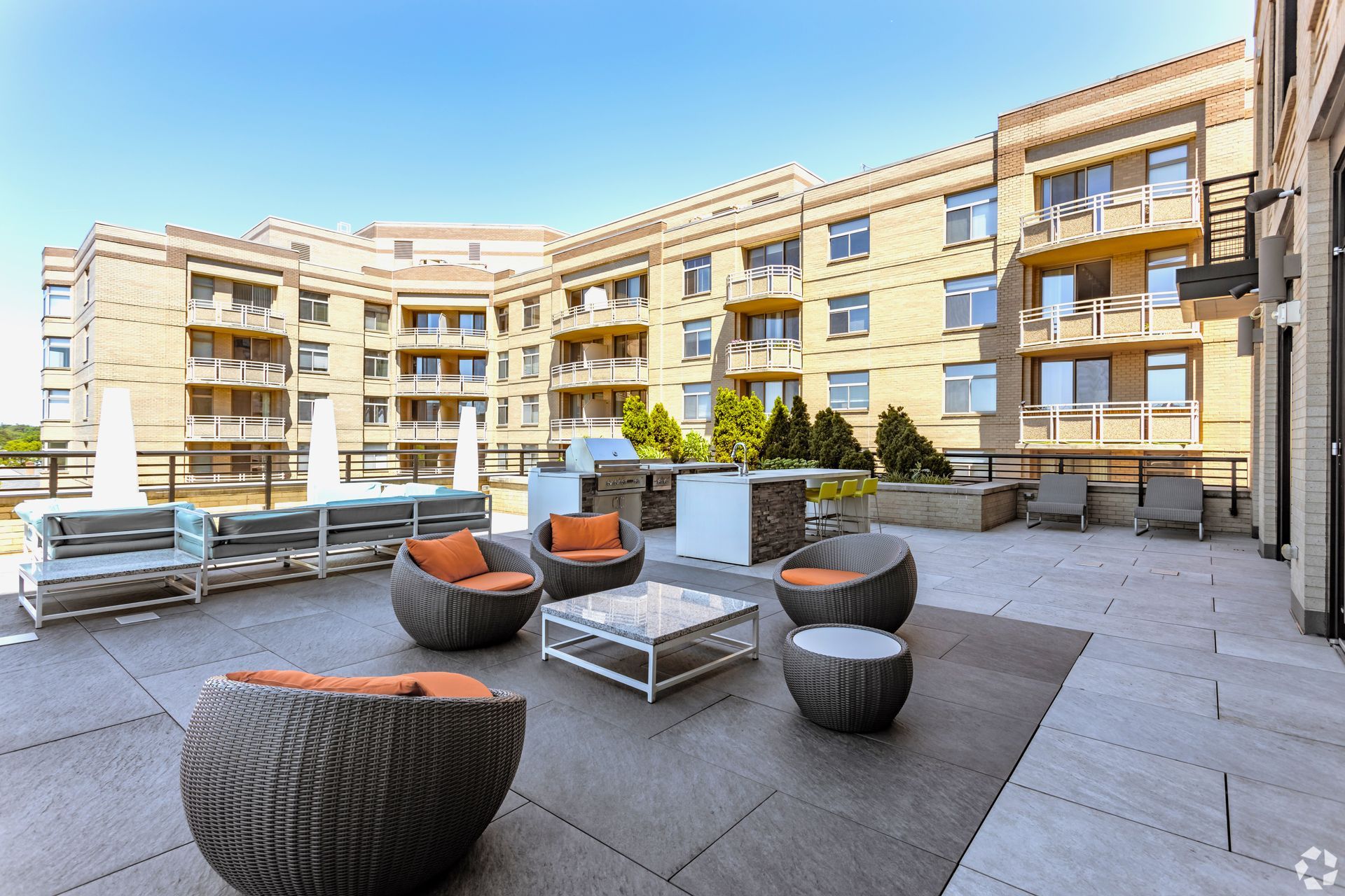 A patio with chairs and a coffee table in front of a building at Solaire 7077 Woodmont in Bethesda, MD.