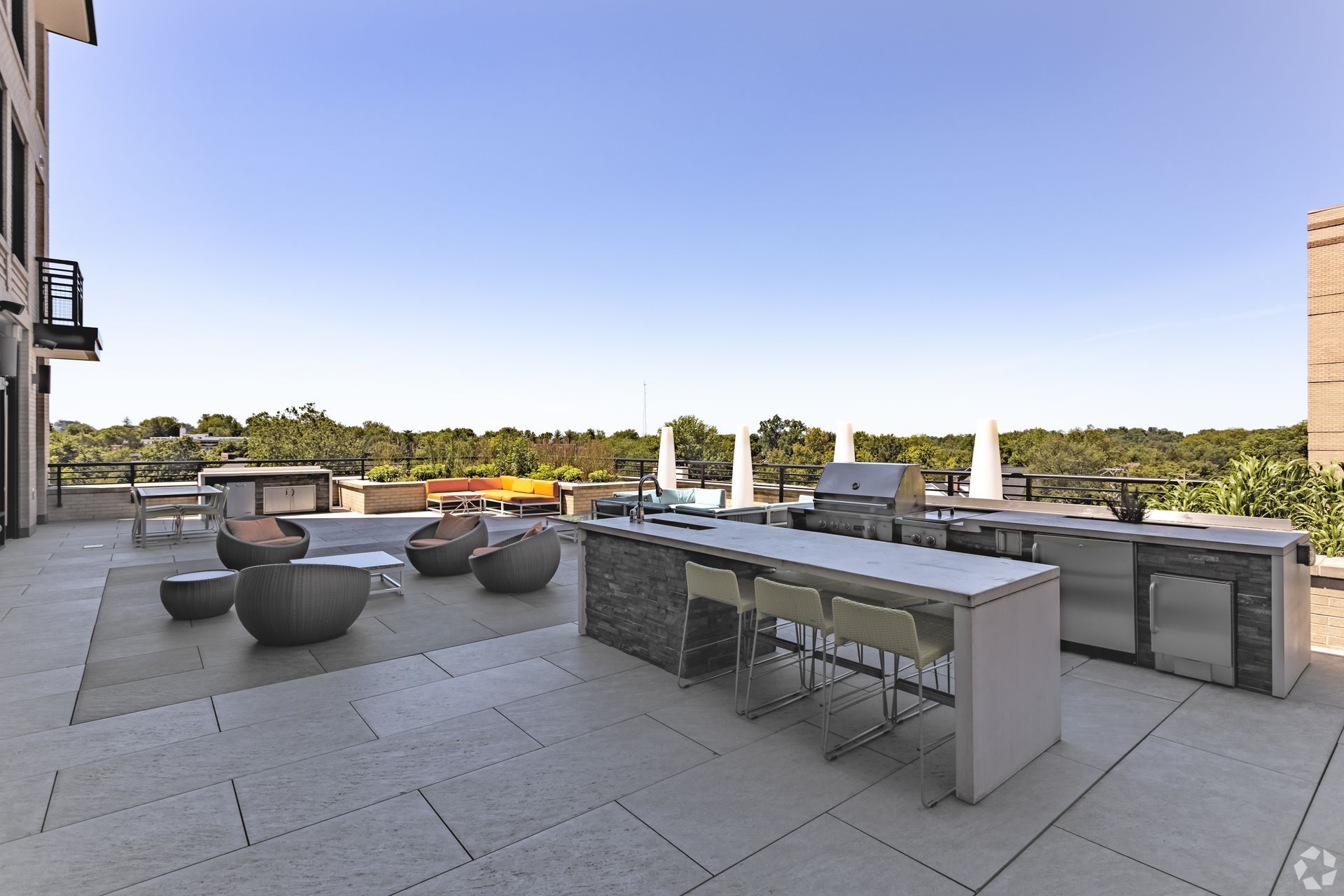 Rooftop patio with lounge seating, dining tables, and river views under a clear sky at Solaire 7077 Woodmont in Bethesda, MD.