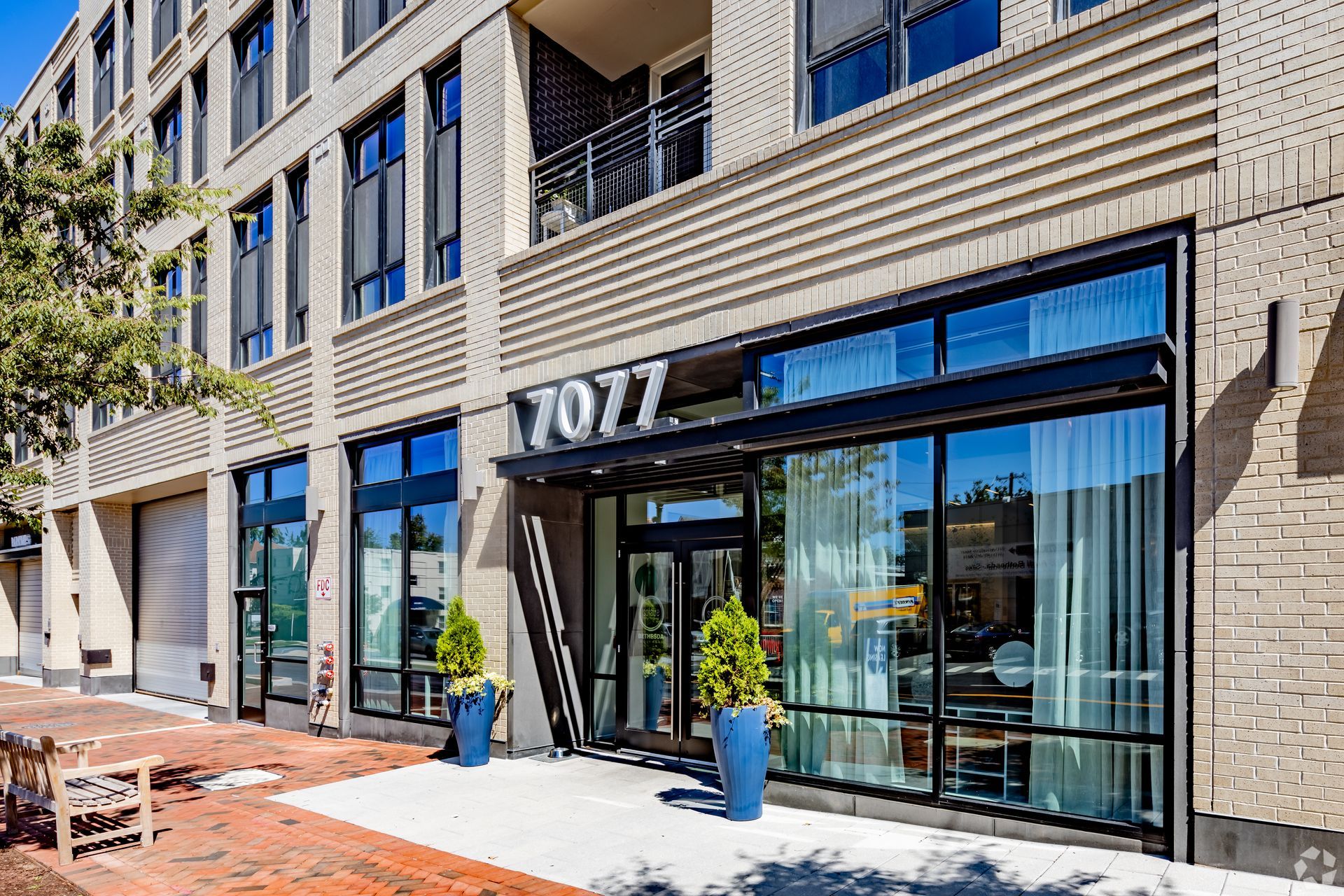 A large building with a lot of windows and a sign that says ' 7777 ' at Solaire 7077 Woodmont in Bethesda, MD.