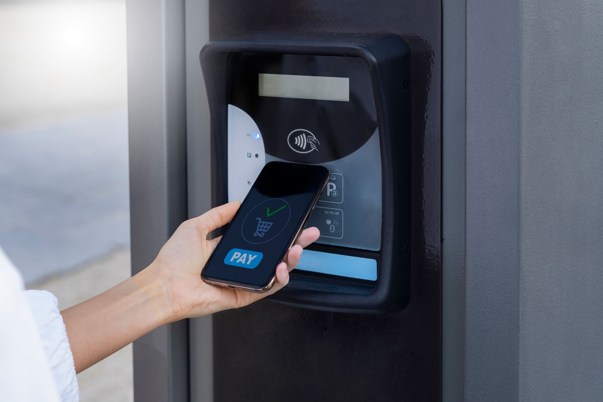Person taps a smartphone on a wall-mounted access reader to unlock a door