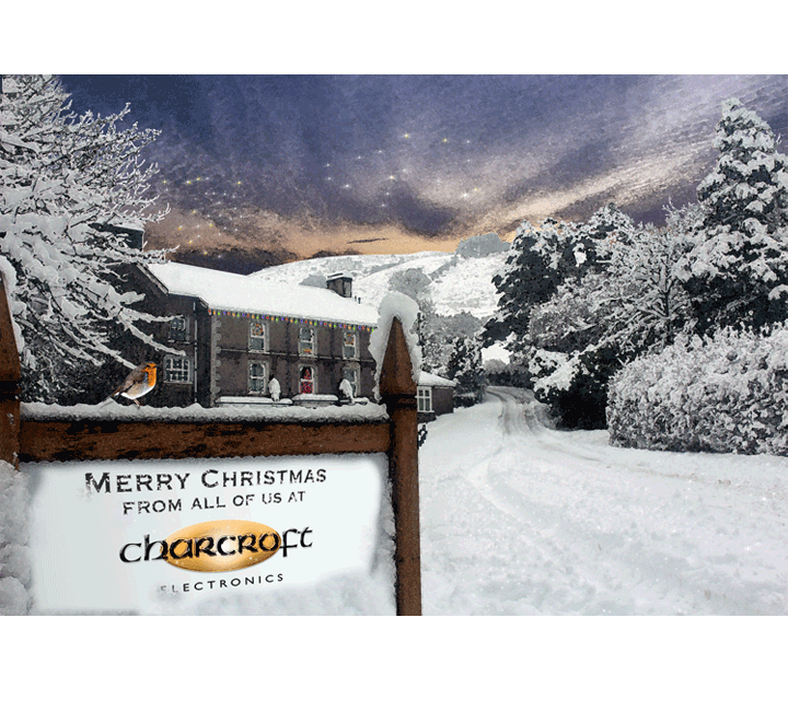 Snowy mountain village entrance sign reading “Merry Christmas from all of us at Chamonix,” under a winter sky