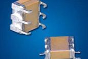 Two small metallic electronic components with side pins on a blue background