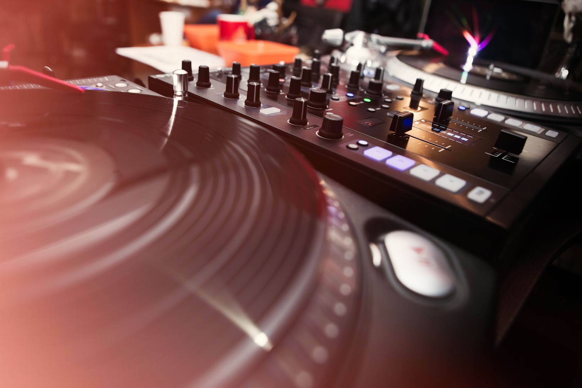 DJ turntable and mixer with glowing lights in a dim club setting