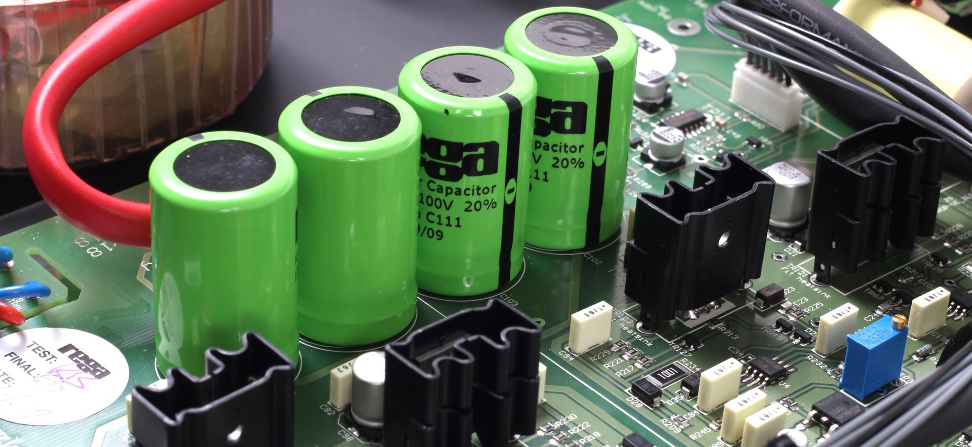 Close-up of green cylindrical capacitors and other components on a circuit board