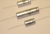 Three silver cylindrical components on a beige surface, each with thin wire leads.