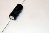 Black cylindrical object with a wire attached, lying on a white surface.