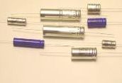 Assorted silver and purple cylindrical batteries or flashlight components arranged on a white background
