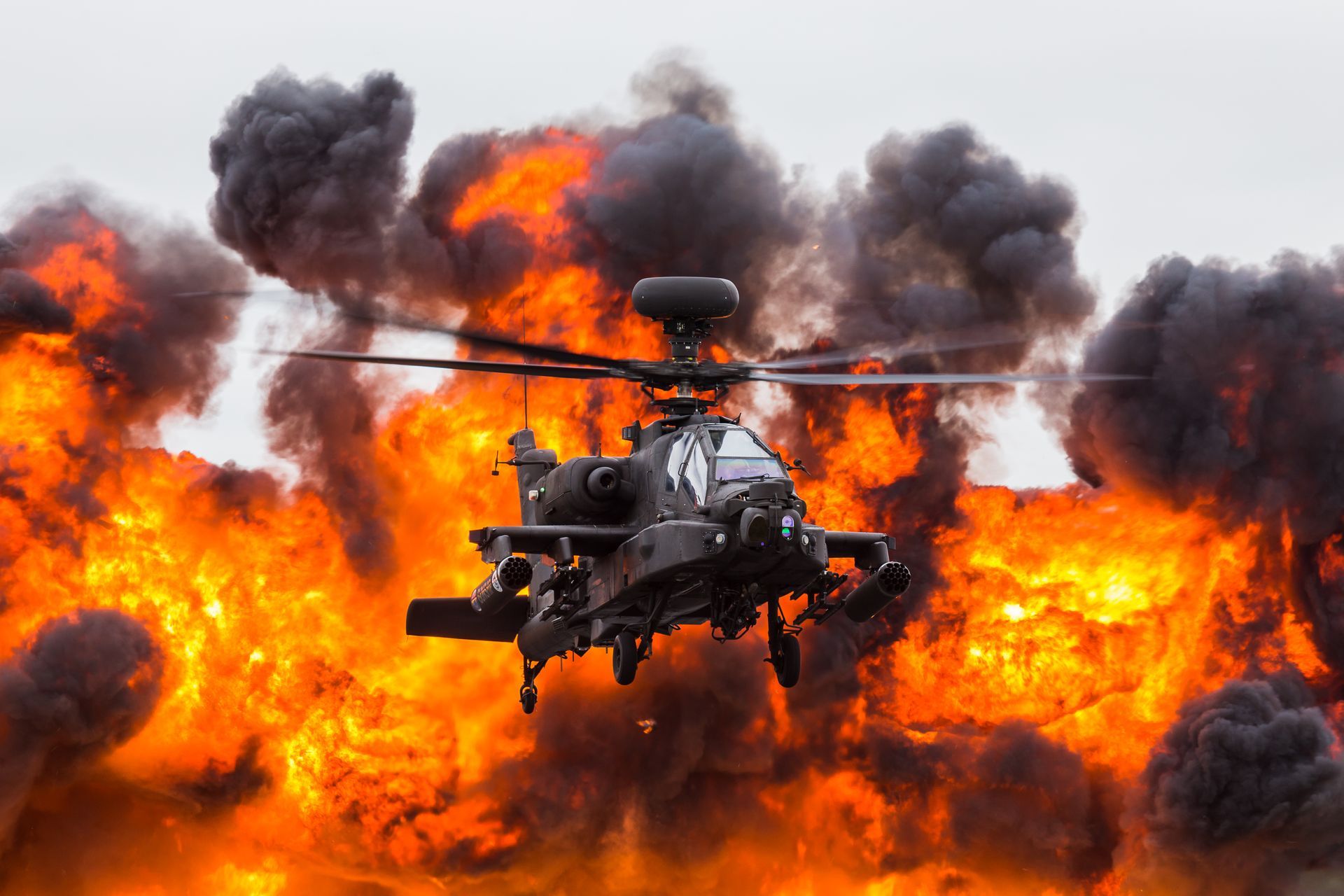 Attack helicopter flying amid huge flames and thick black smoke