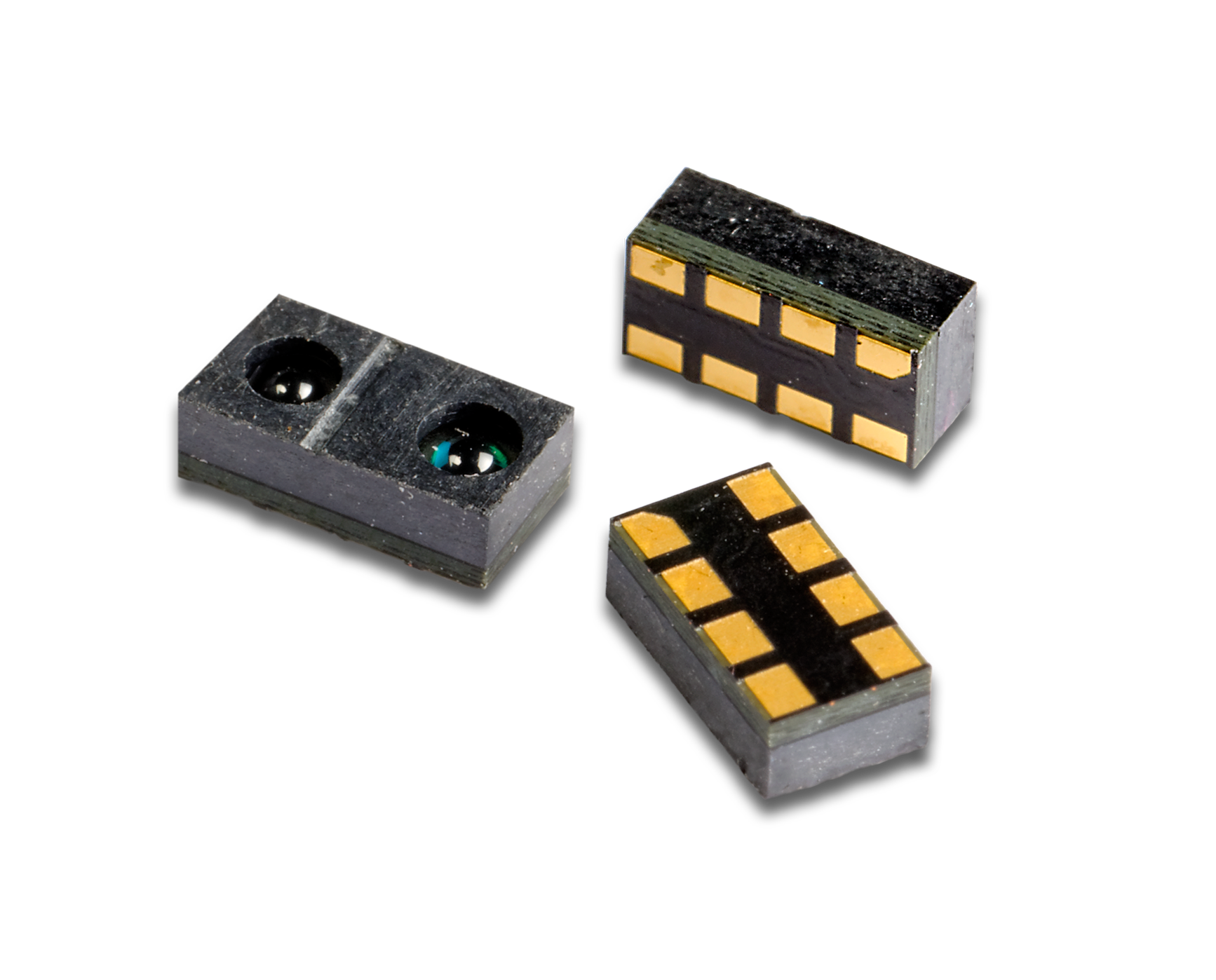 Three tiny black and gold electronic sensors or components on a white background