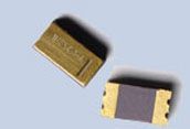 Two small gold-and-gray electronic components on a light blue background