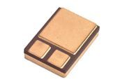 Copper and black electronic component chip with rectangular pads on a white background