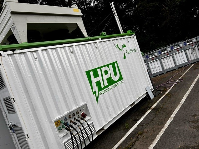 White HPU shipping container with cables and equipment at night, angled along a paved lot