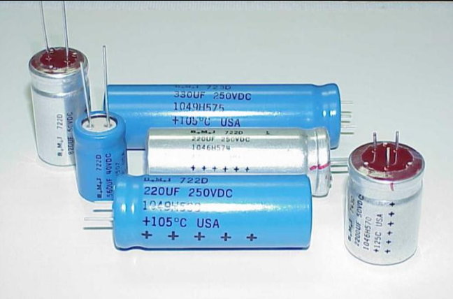 Assorted blue and silver cylindrical capacitors with wire leads on a white background