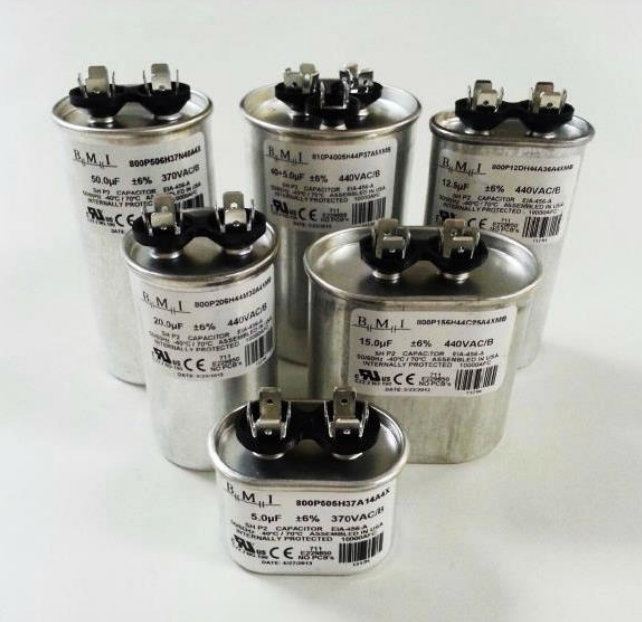 Six silver metal capacitors with black tops arranged in a group on a white background