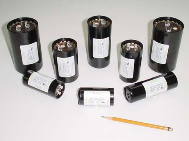 Black film canisters scattered on a white surface with a pencil for scale