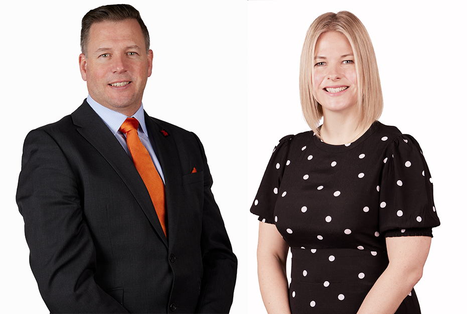 Two professionals posing against a white background, one in a black suit with an orange tie, one in a black polka-dot dress