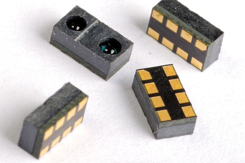 Small gray electronic components with gold contacts, shown from different angles on a white background