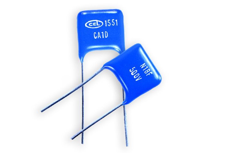 Two blue film capacitors with silver leads on a white background