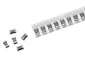 Small black-and-white electronic components beside a strip of connected surface-mount parts