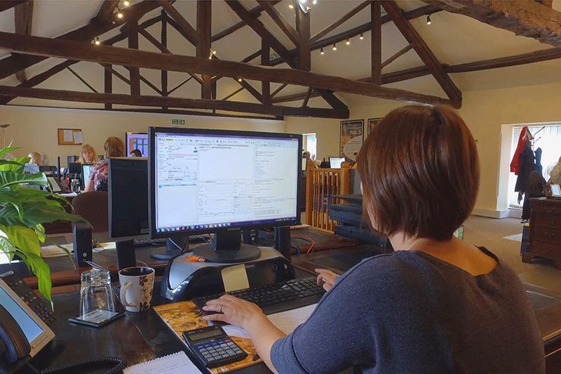 Person working at a desk with a computer in an open office space