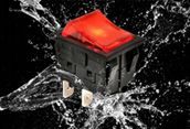 Black switch with a glowing red top splashing through water