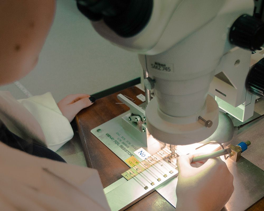 Person using a microscope to inspect a sample under bright lab light