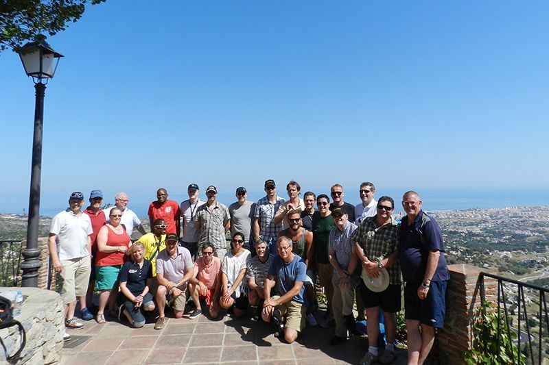 Group of people posing on a scenic overlook with city and ocean views under a bright blue sky
