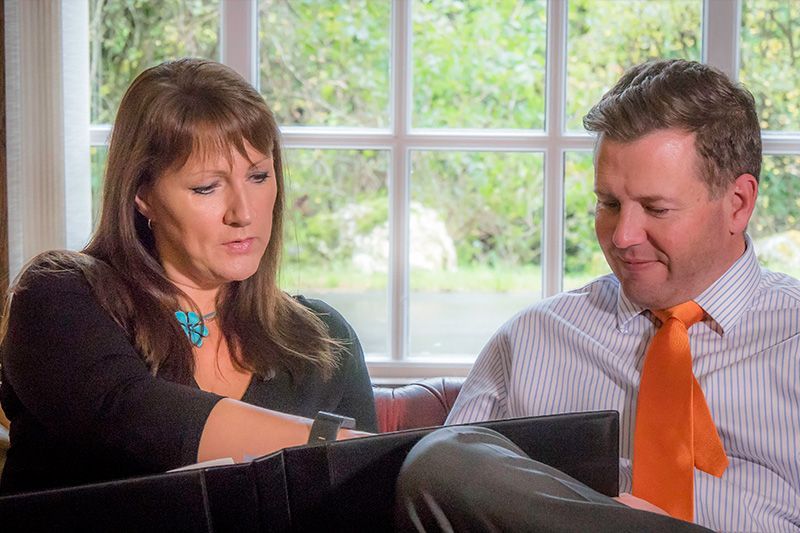 Two people reviewing a document together at a table by a bright window