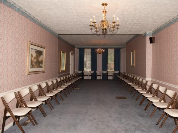 Long hallway with rows of folding chairs along both walls and chandeliers overhead