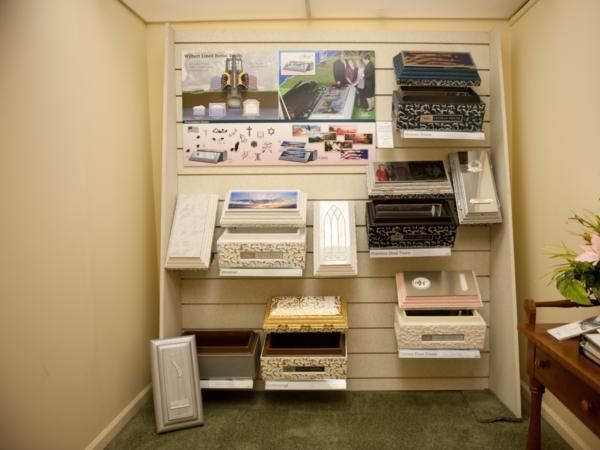 Wall display of books, brochures, and fabric swatches in a beige room, with samples arranged on shelves.