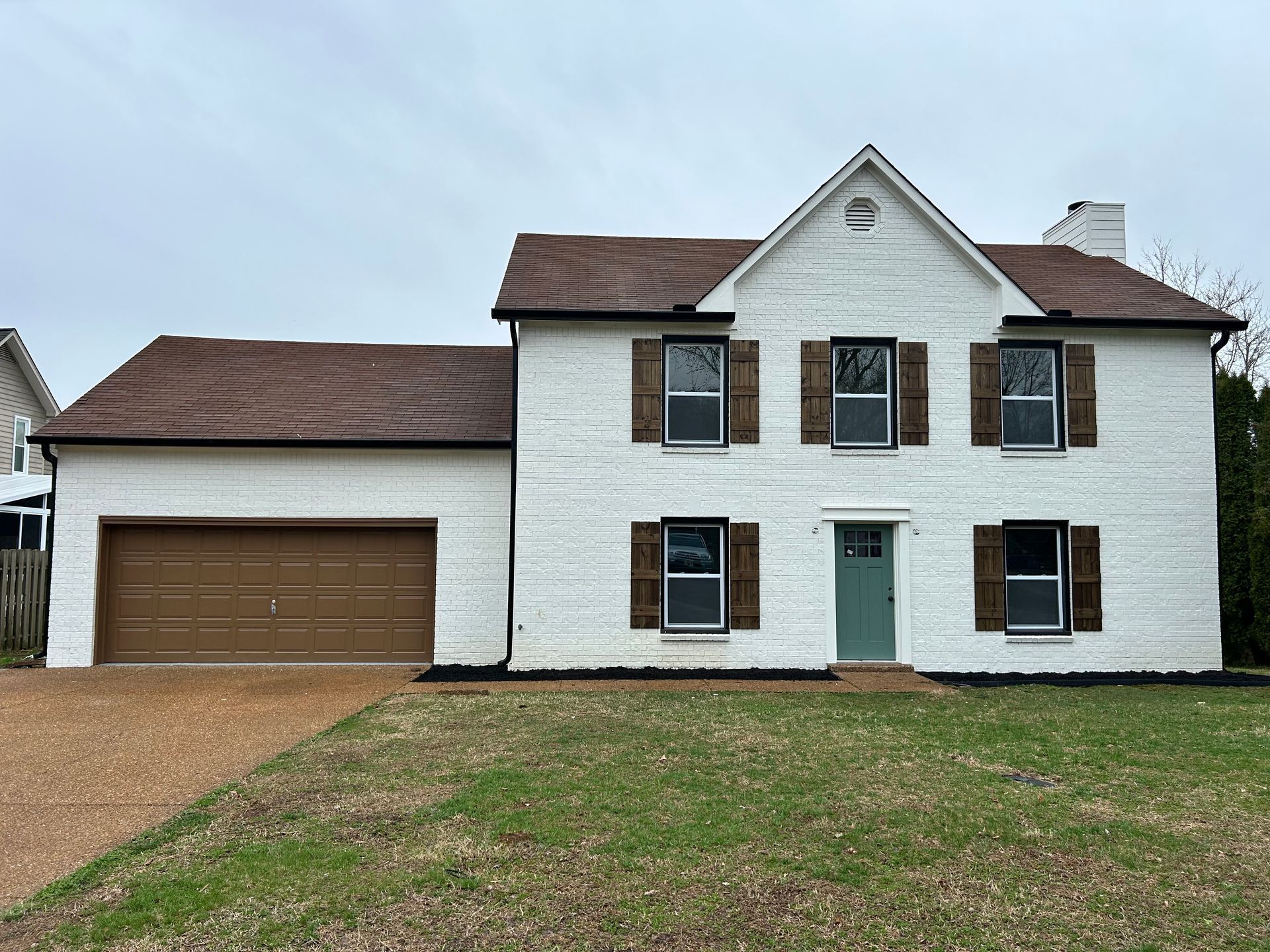 A large white house with brown shutters and a garage.