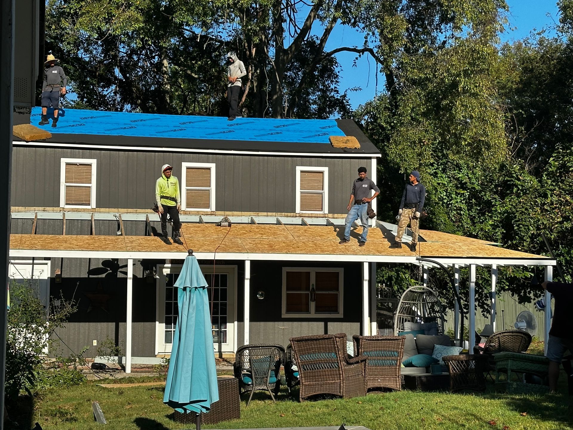 A group of men are working on the roof of a house.