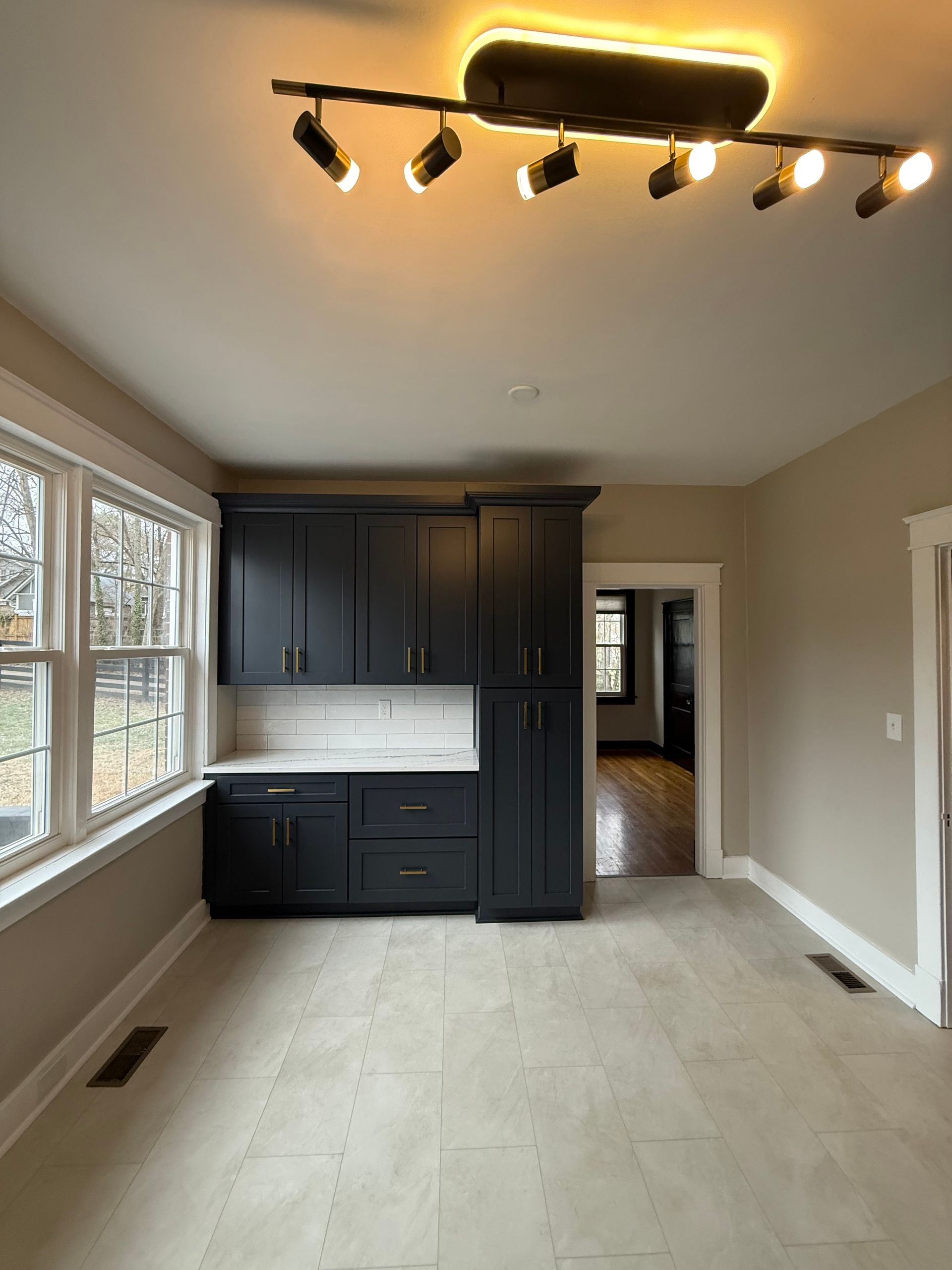 An empty kitchen with black cabinets and a ceiling light