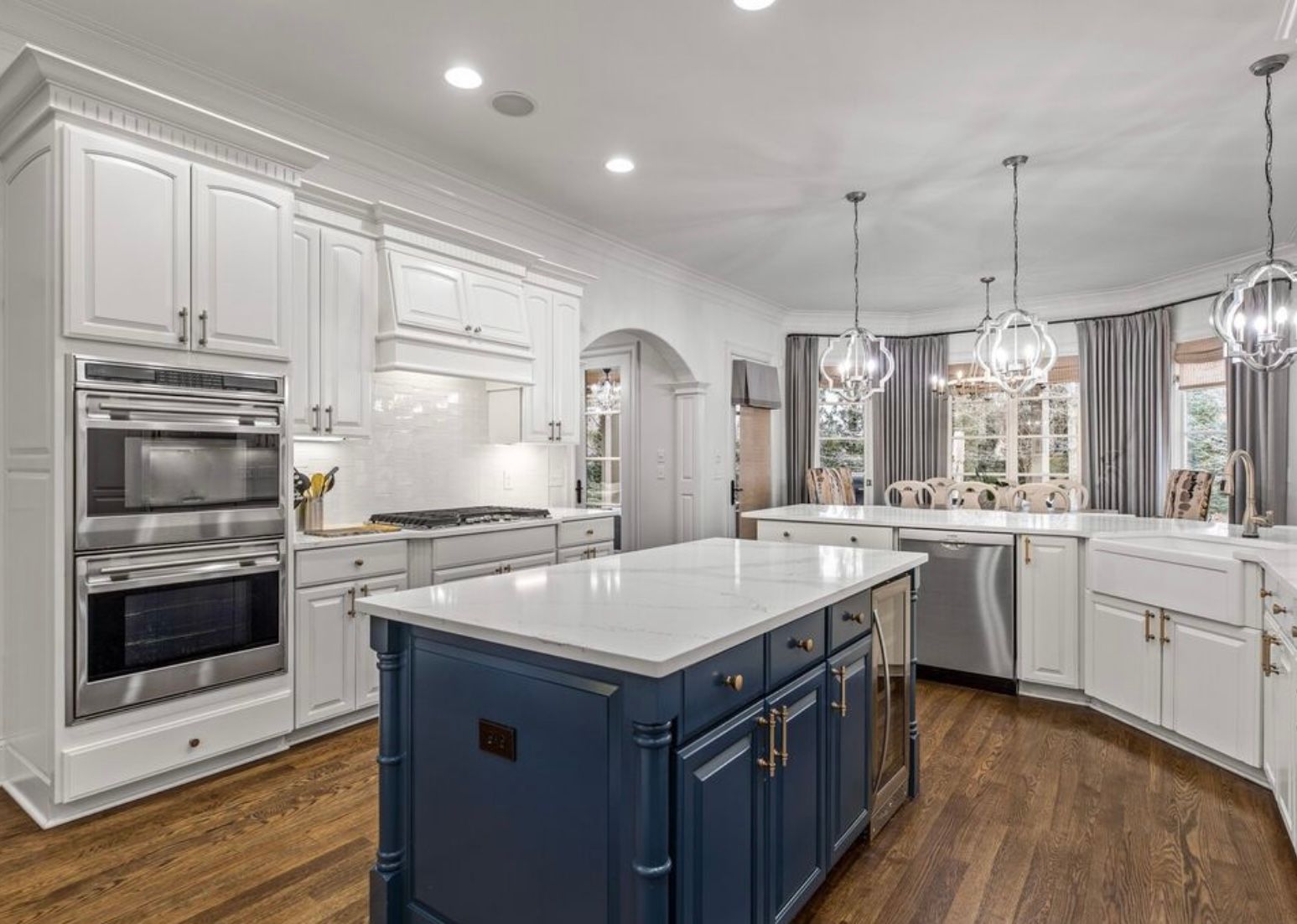A kitchen with white cabinets and stainless steel appliances and a large blue island.