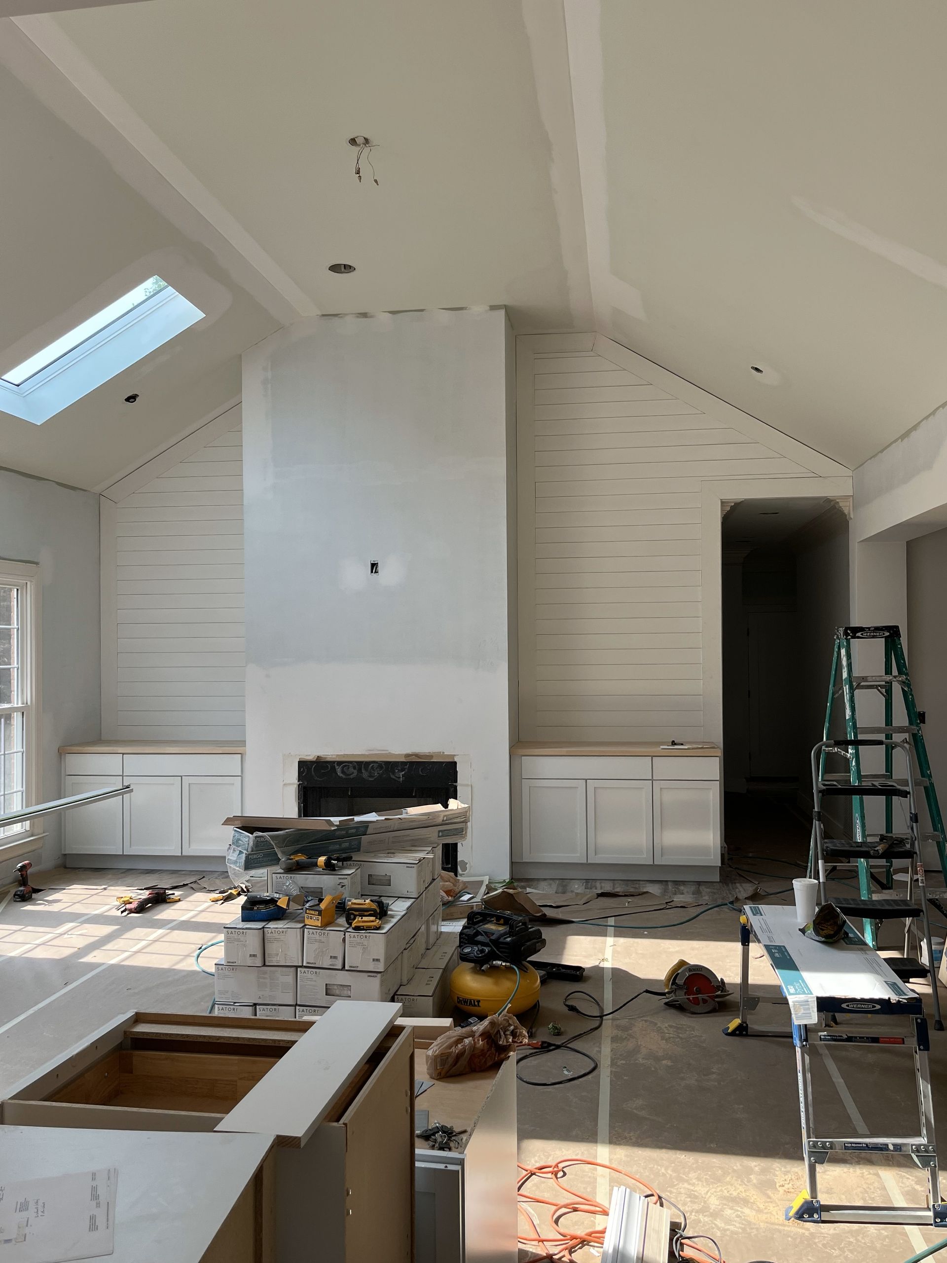 A living room with a fireplace and a skylight in the ceiling.