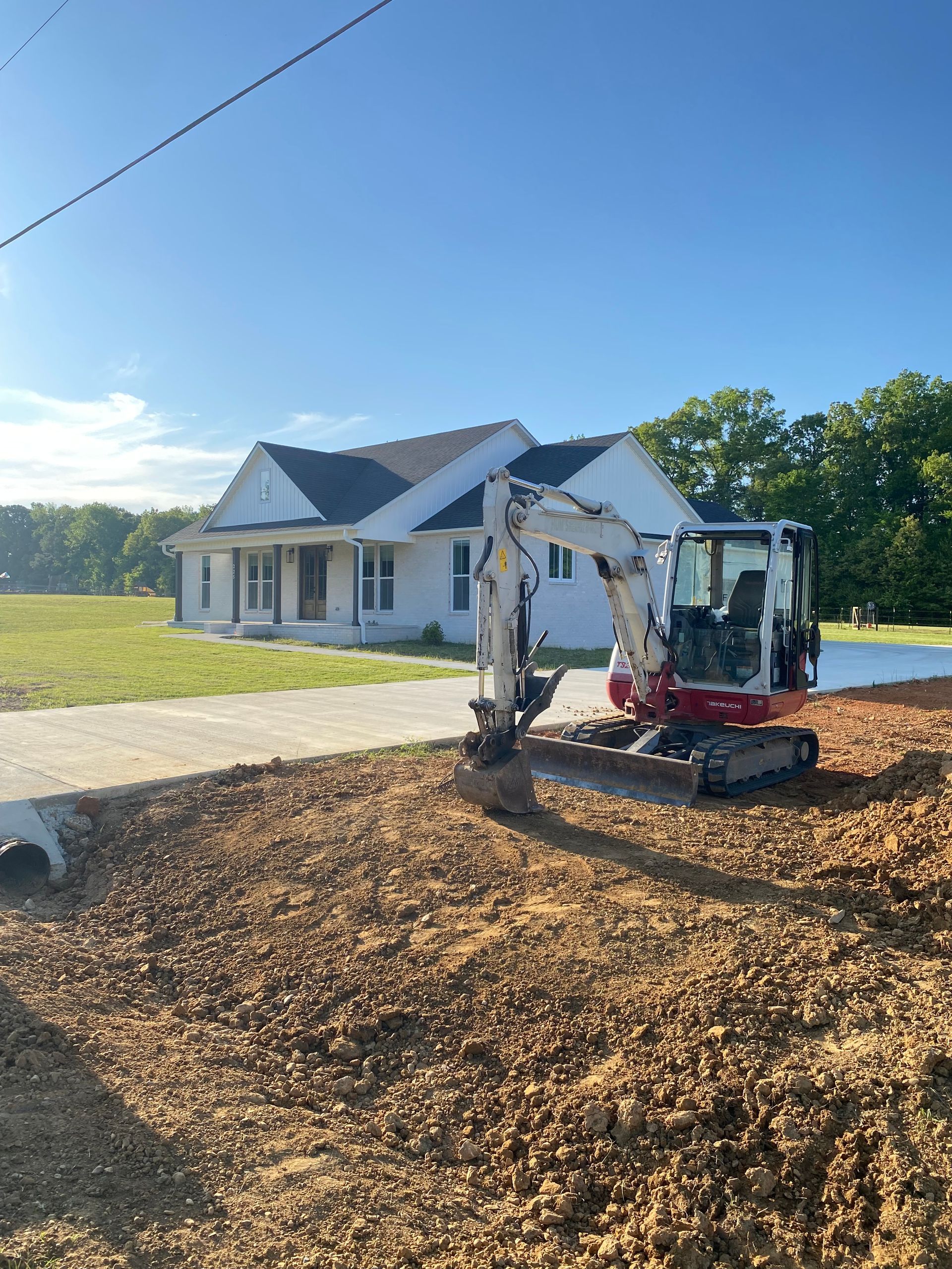 A small excavator is digging a hole in front of a house.