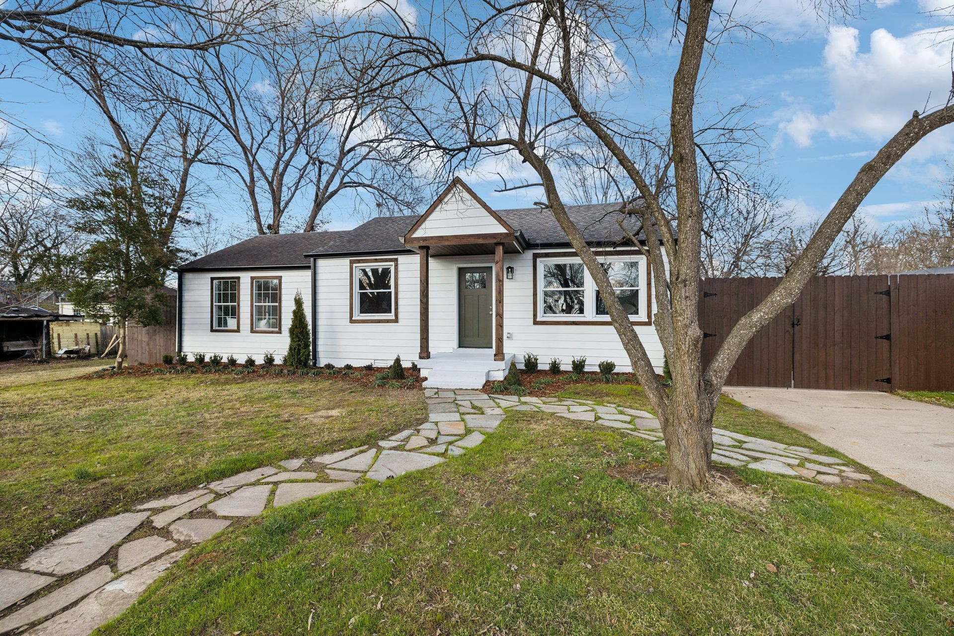 A white house with a stone walkway leading to it is for sale.