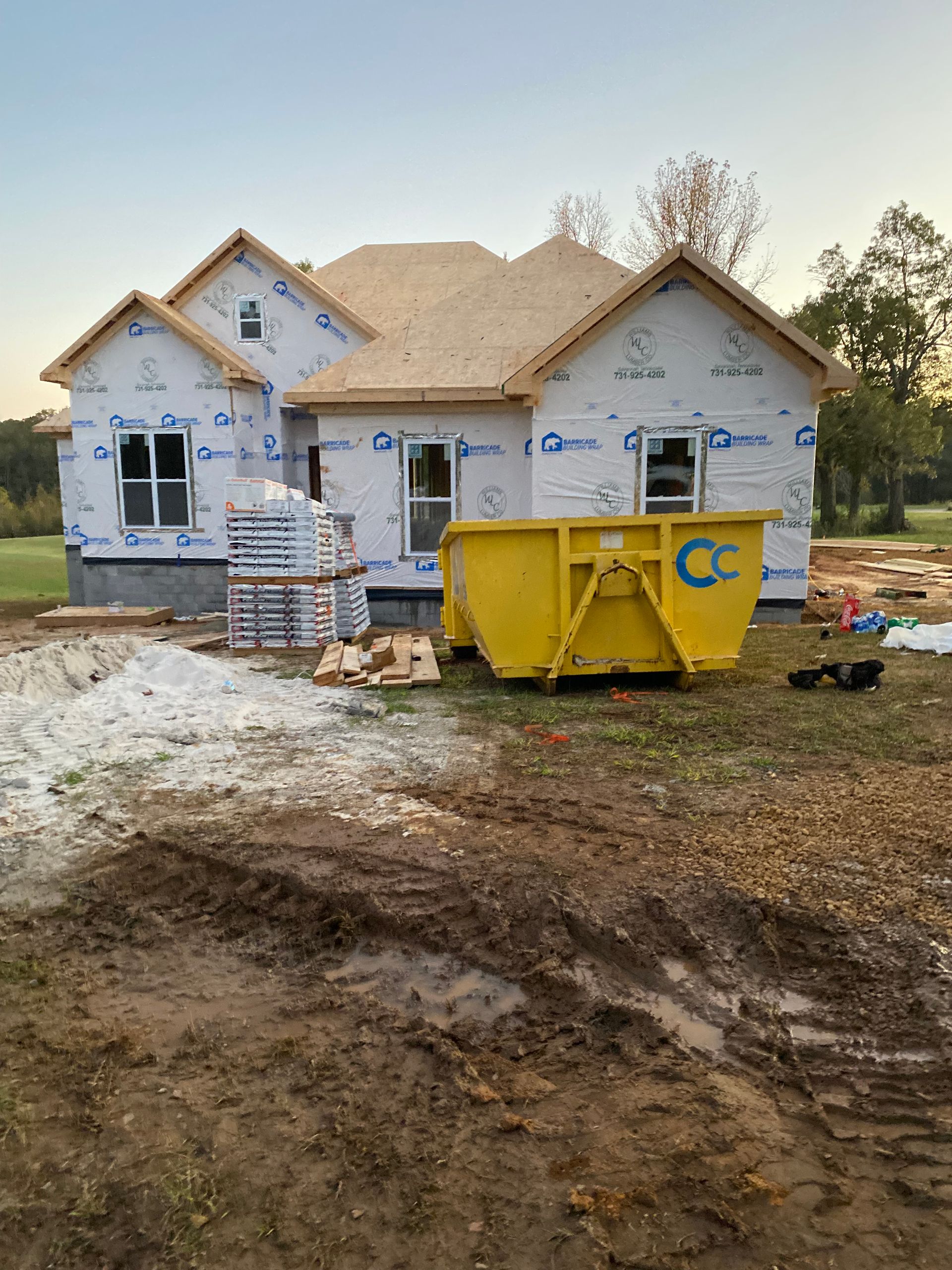 A house under construction with a yellow dumpster in front of it.