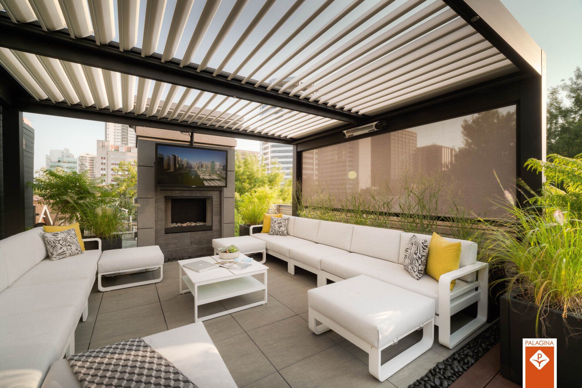 Patio sul tetto con mobili bianchi, camino, TV e tetto a pergola retrattile.