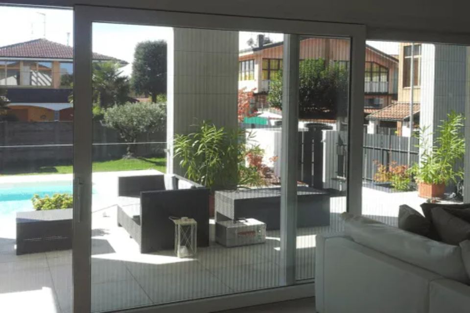 Le porte a vetri si aprono sul patio con piscina e area salotto nel soleggiato cortile sul retro.