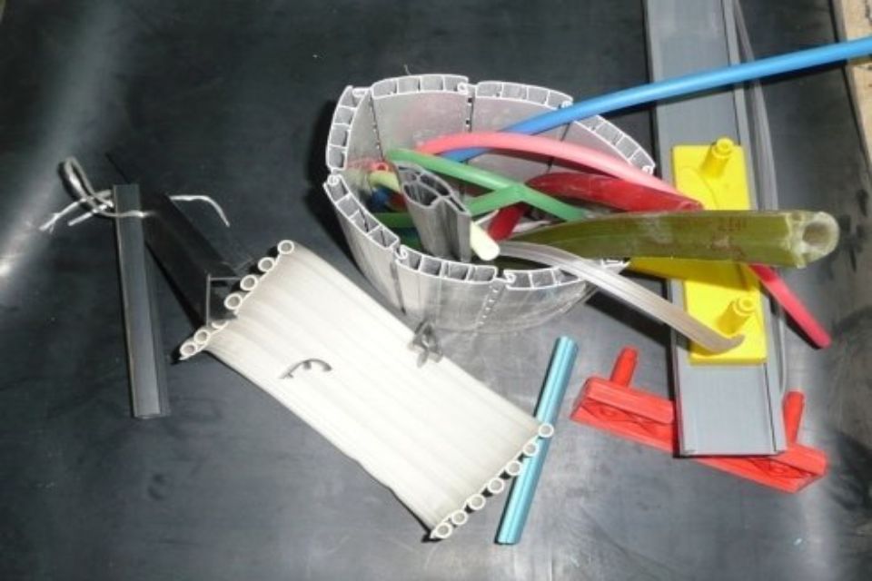 Pezzi di plastica assortiti in una vasca, di vari colori e forme, sparsi su una superficie scura.