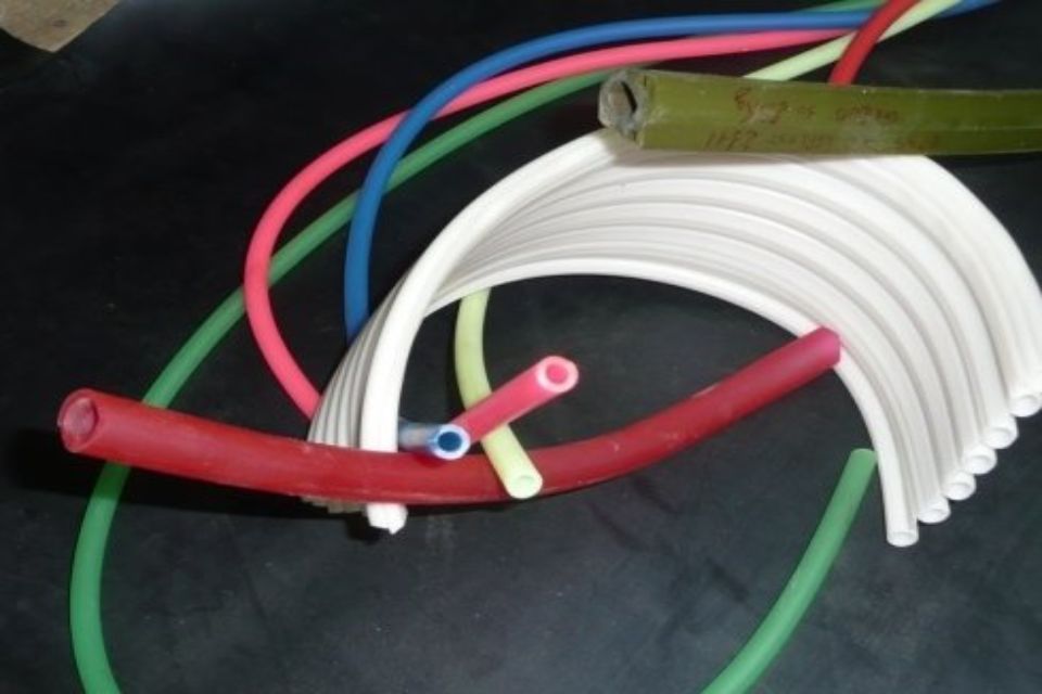Vari tubi di gomma colorati, tra cui rosso, verde, blu e bianco, disposti su una superficie scura.
