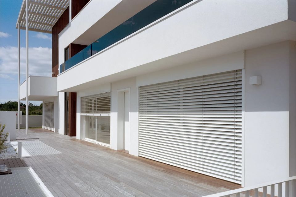 Moderno edificio bianco con persiane a stecche orizzontali all'esterno.