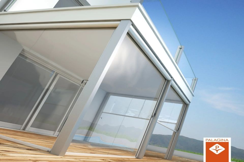 Moderno balcone con pareti in vetro e tende retrattili, con vista sul cielo soleggiato.