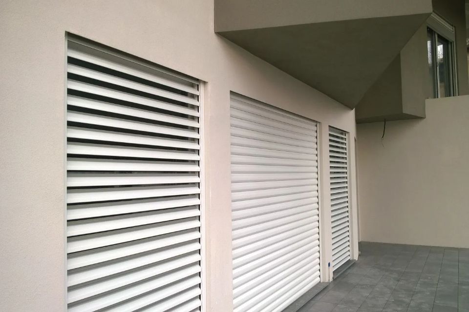 Persiane bianche sulla facciata beige di un edificio.