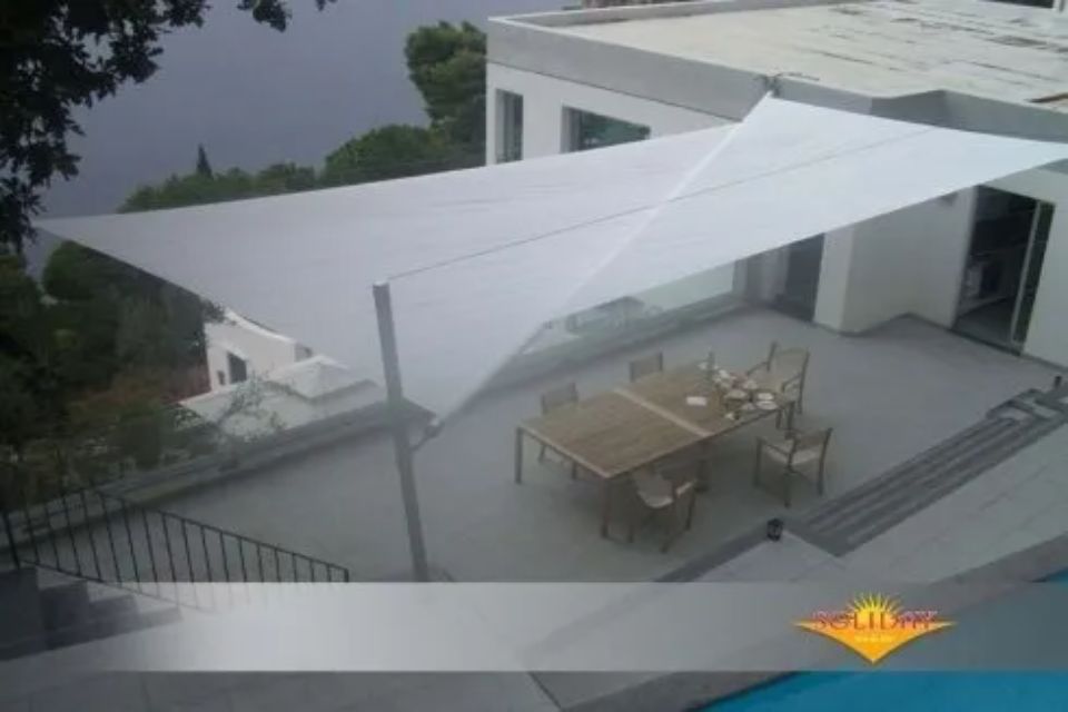 Vele ombreggianti bianche sul patio esterno con tavolo da pranzo e sedie.