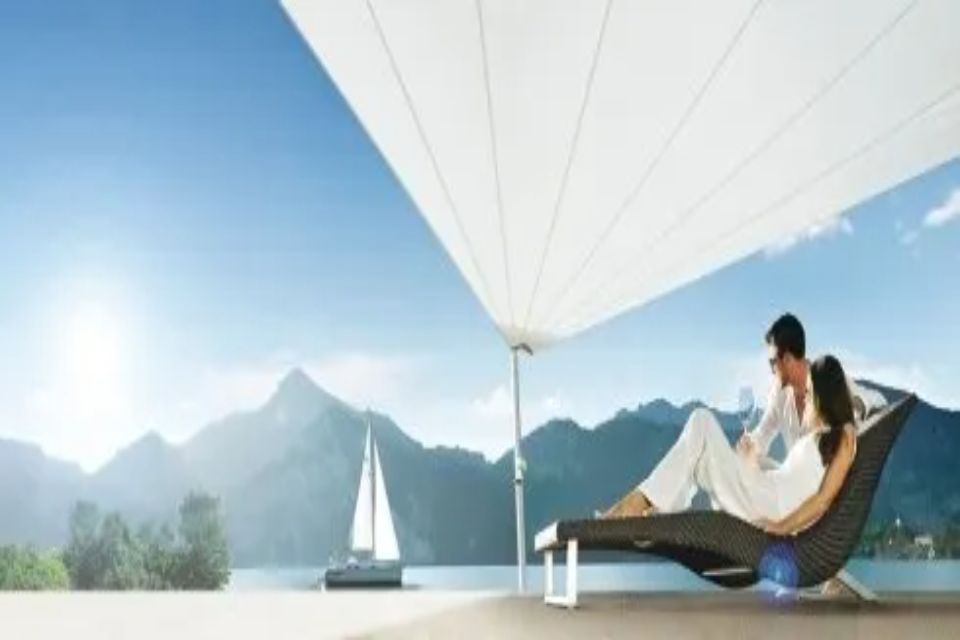 Coppia che si rilassa su una sedia a sdraio sotto un baldacchino bianco, con vista sul lago e sulle montagne.
