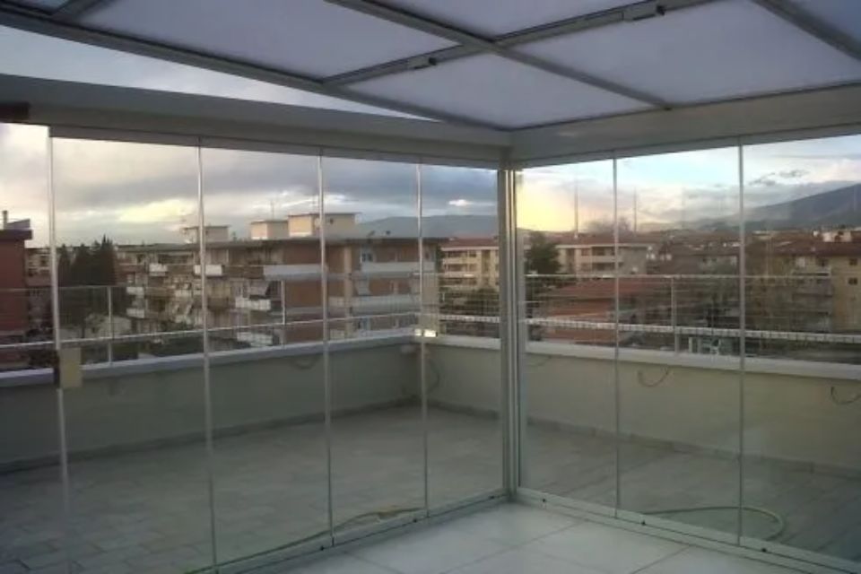 Balcone con vetrate e vista sugli edifici e sul cielo al tramonto.